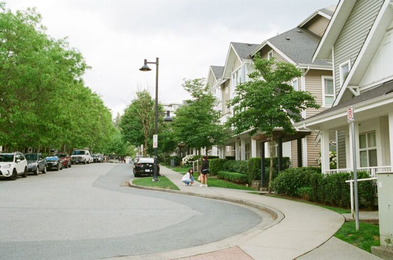 Charming Vancouver street with families enjoying a day outdoors among lined trees and houses. Urban community scene.